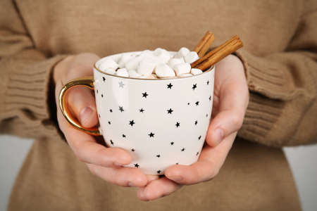 Woman holding cup of delicious hot chocolate with marshmallows and cinnamon sticks, closeupの写真素材