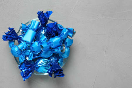 Candies in blue wrappers on gray table, top view. Space for textの写真素材
