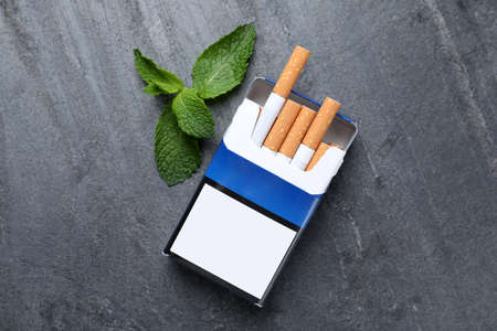 Pack of menthol cigarettes and mint on gray table, flat layの写真素材