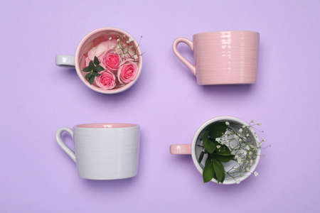 Cups with flowers on violet background, flat layの写真素材