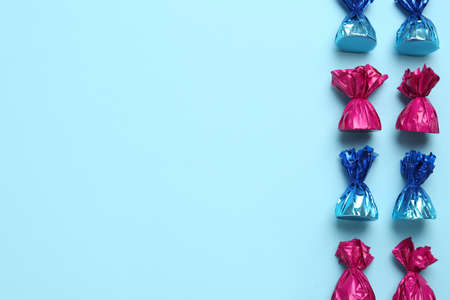 Candies in colorful wrappers on light blue background, flat lay. Space for textの写真素材