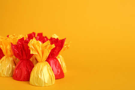 Candies in colorful wrappers on yellow background. Space for textの写真素材