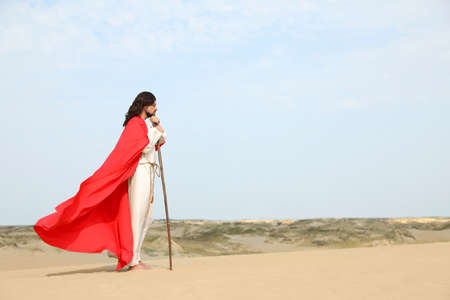 Jesus Christ walking with stick in desert. Space for textの写真素材