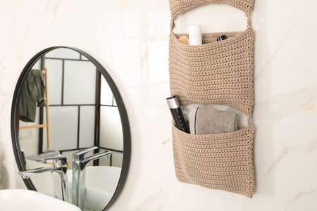 Knitted organizer hanging on wall in bathroomの写真素材