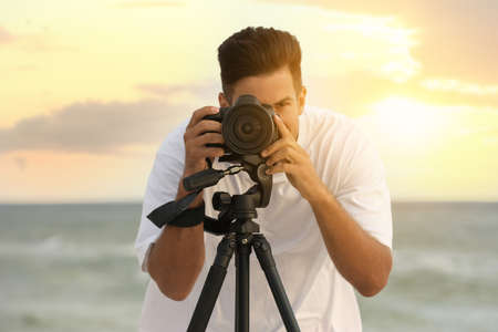 Photographer working with professional camera near seaの写真素材