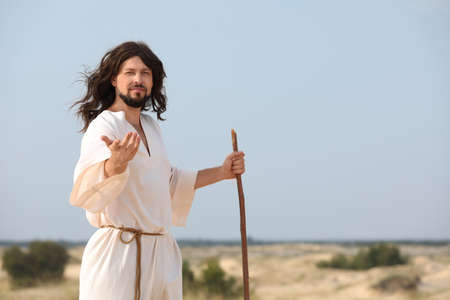 Jesus Christ walking with stick in desert. Space for textの写真素材