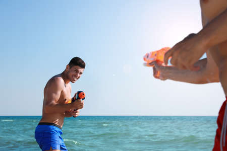 Friends with water guns having fun in seaの写真素材