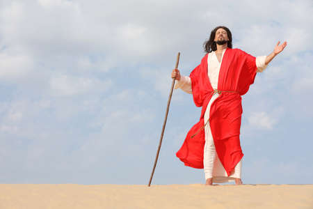 Jesus Christ walking with stick in desert. Space for textの写真素材