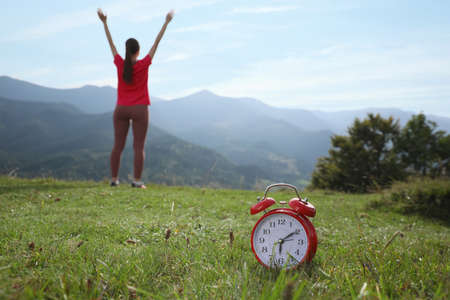 Woman doing morning exercise in mountains, focus on alarm clockの写真素材