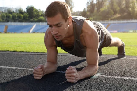 Sporty man doing plank exercise at stadiumの写真素材