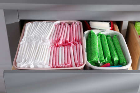 Open cabinet drawer with menstrual pads, tampons and pantyliners, closeupの写真素材