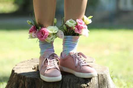 Woman standing on wooden stump outdoors with flowers in socks, closeupの写真素材