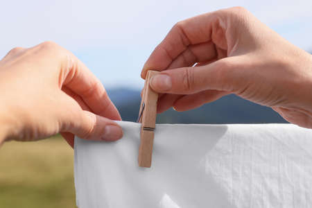 Woman hanging clean laundry with clothespin on washing line outdoors, closeupの写真素材