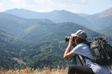 Professional photographer taking picture with modern camera in mountains. Space for textの写真素材
