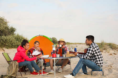 Friends resting near camping tent on sandy beachの写真素材
