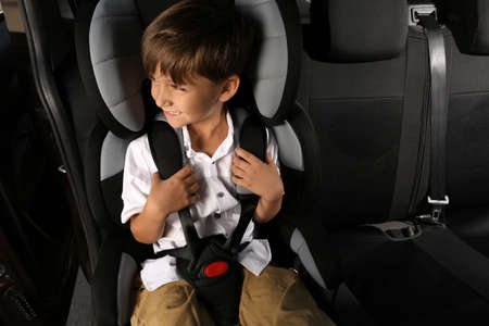 Little boy fastened with car safety belt in child seatの写真素材