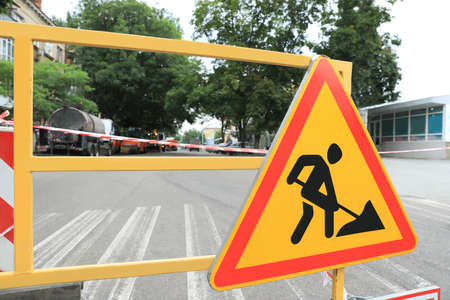 Barricade with road construction sign on city street, closeup. Repair works