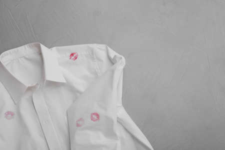 Men's shirt with lipstick kiss marks on light background, top view. Space for textの写真素材