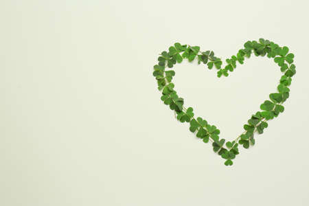 Heart of green clover leaves on light background, flat lay. Space for textの写真素材