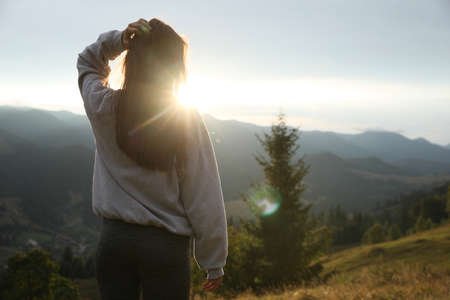 Beautiful young woman enjoying her time in mountains, back view. Space for textの写真素材