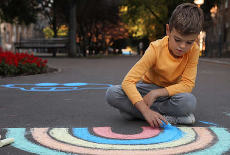 Child drawing rainbow with chalk on asphaltの写真素材