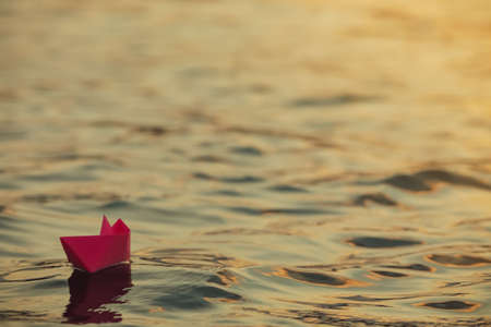Paper boat floating on water outdoors. Space for textの写真素材