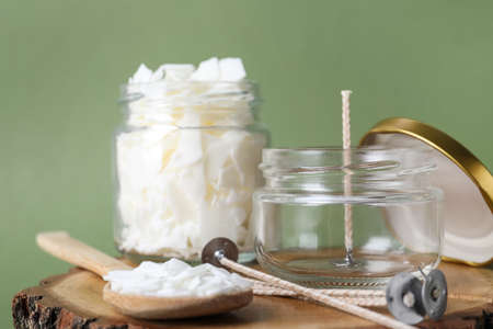 Ingredients for homemade candle on wooden stump against green background, closeupの写真素材