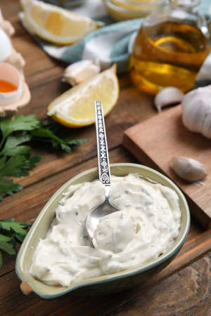Tasty tartar sauce and ingredients on wooden tableの写真素材