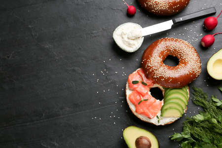 Delicious bagel with cream cheese, salmon and avocado on black table, flat lay. Space for textの写真素材