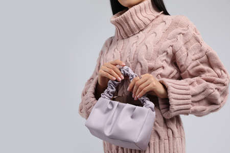 Fashionable woman with stylish bag on light background, closeup. Space for textの写真素材