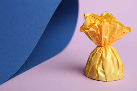 Candy in yellow wrapper on color background. Space for textの写真素材