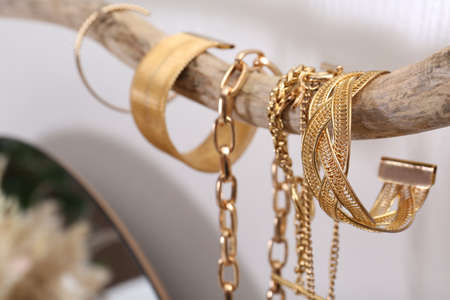 Beautiful bracelets and necklaces on wooden branch indoors, closeupの写真素材