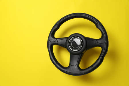 New black steering wheel on yellow background, space for textの写真素材