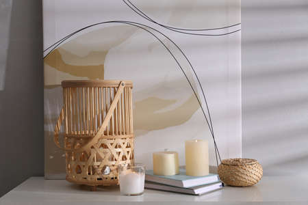 Burning scented candles and books on white table near light wallの写真素材