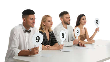 Panel of judges holding different score signs at table on white backgroundの写真素材
