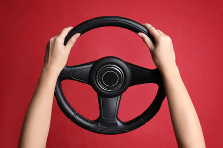 Woman holding steering wheel on red background, closeupの写真素材