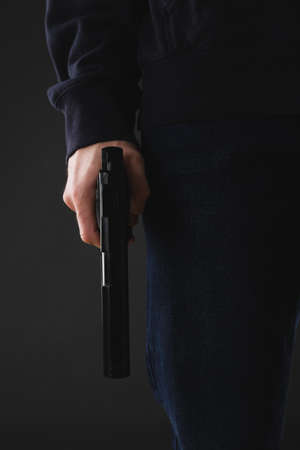 Man holding gun on black background, closeupの写真素材