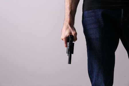 Man holding gun on gray background, closeup. Space for textの写真素材