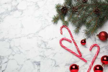Tasty candy canes and Christmas decor on white marble table, flat lay. Space for textの写真素材