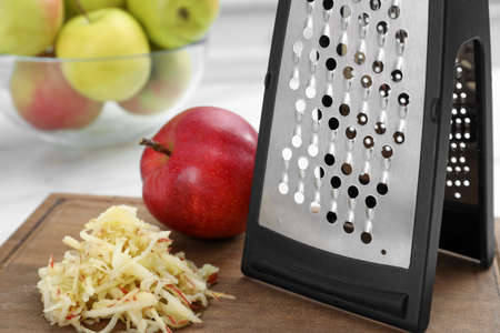 Grater and fresh ripe apple on wooden board, closeupの写真素材