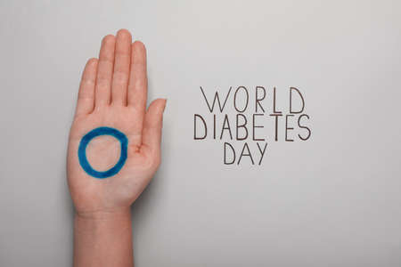 Woman showing palm with blue circle near text World Diabetes Day on light background, closeupの写真素材