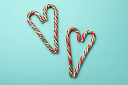 Hearts made of sweet Christmas candy canes on turquoise background, flat lay