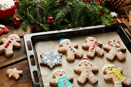 Making homemade Christmas cookies. Gingerbread people and festive decor on wooden table
