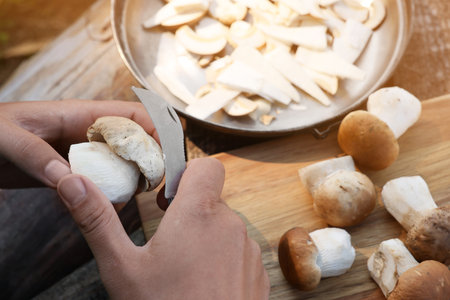 Man cutting mushroom with knife at wooden table, closeupの写真素材