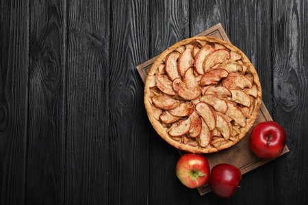 Delicious apple pie and fresh fruits on black wooden table, top view. Space for textの写真素材