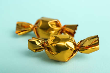 Candies in golden wrappers on light blue background, closeupの写真素材