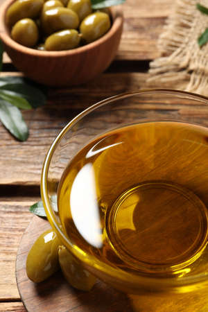 Glass bowl of oil and ripe olives on wooden table, closeupの写真素材