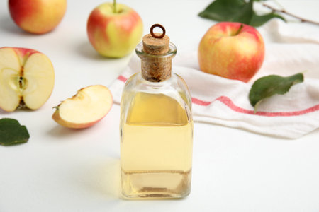 Natural apple vinegar and fresh fruits on white tableの写真素材