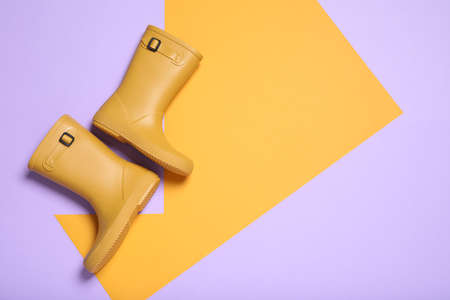 Pair of yellow rubber boots on color background, top view. Space for textの写真素材