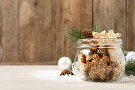 Tasty Christmas cookies in glass jar and festive decor on beige wooden table. Space for textの写真素材